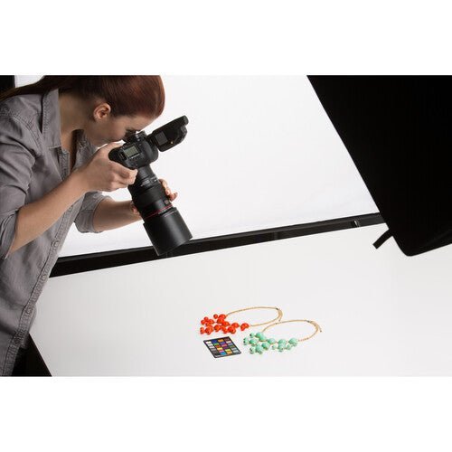 The ColorChecker Classic Mini color reference chart placed next to a camera lens.