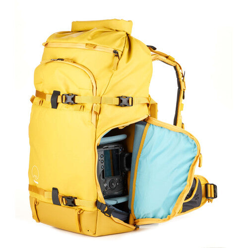 Vibrant yellow Shimoda Action X40 V2 Backpack worn outdoors, showcasing 40L capacity and roll-top closure for photographers.